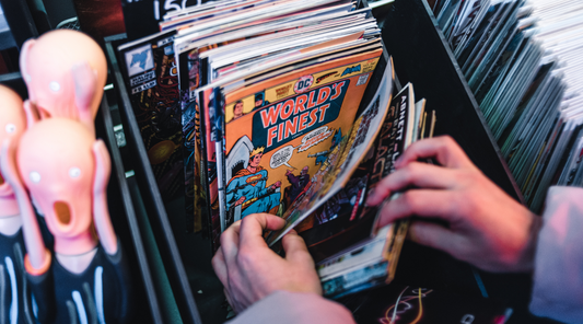 a persons hands going through comics in a short box